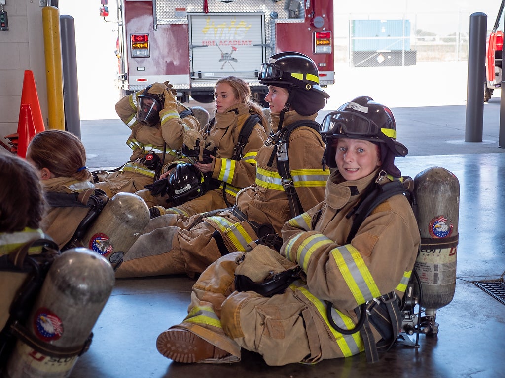 Aims fire science Xplore Academy students wearing fire service gear in the firehouse facility