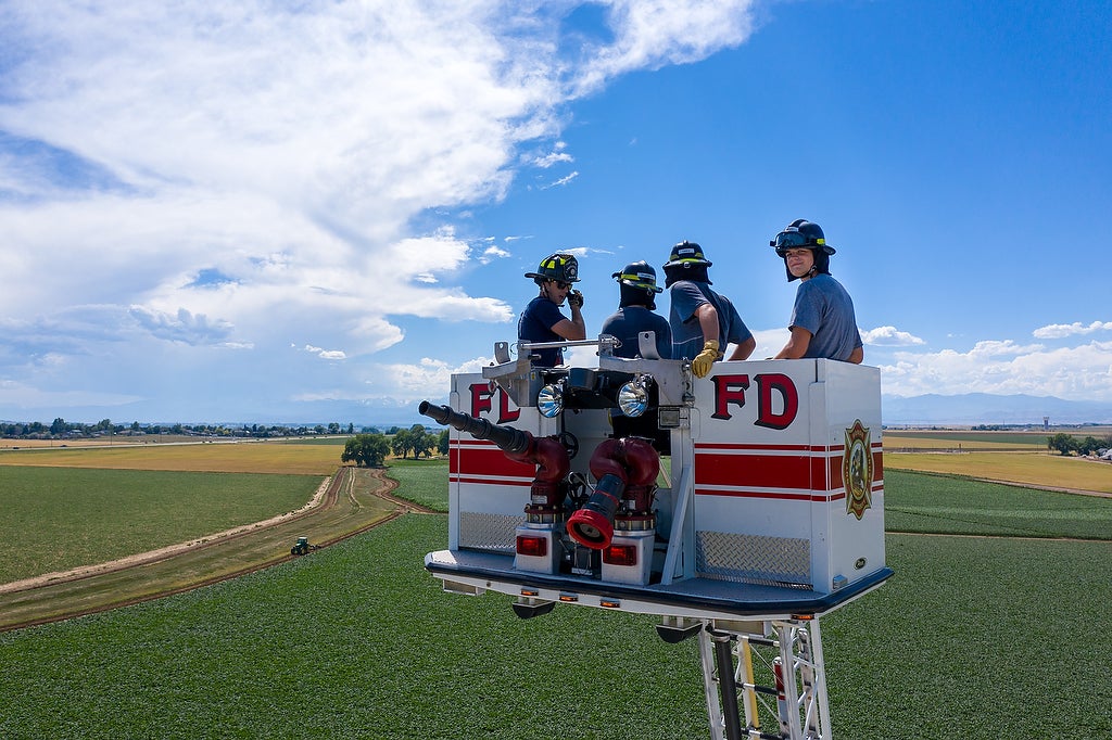Aims fire science Xplore Academy students on a fire truck extension ladder