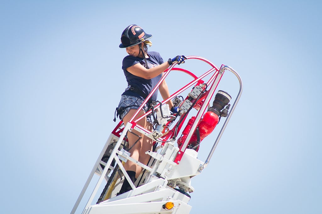 Aims fire science Xplore Academy student on an extension ladder