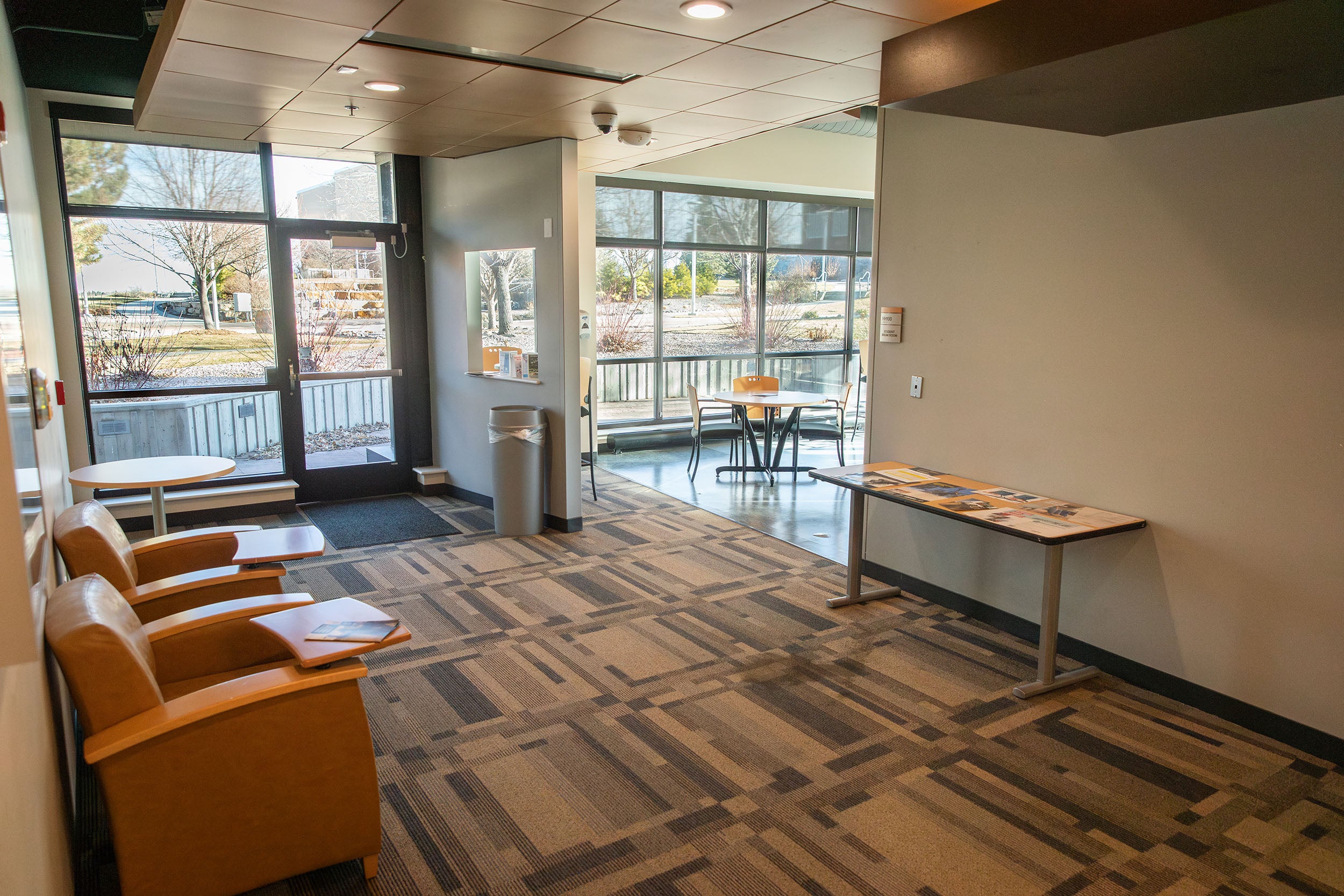 Exterior of the Student Lounge in Horizon Hall. There are chairs, tables, and vending machines.