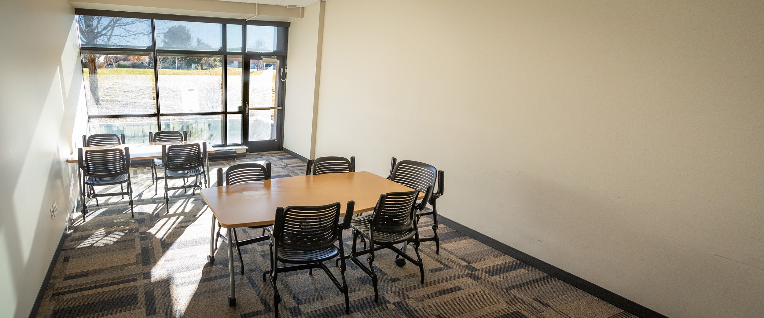 The interior of Horizon Hall study room 102 has tables and chairs for students to use.