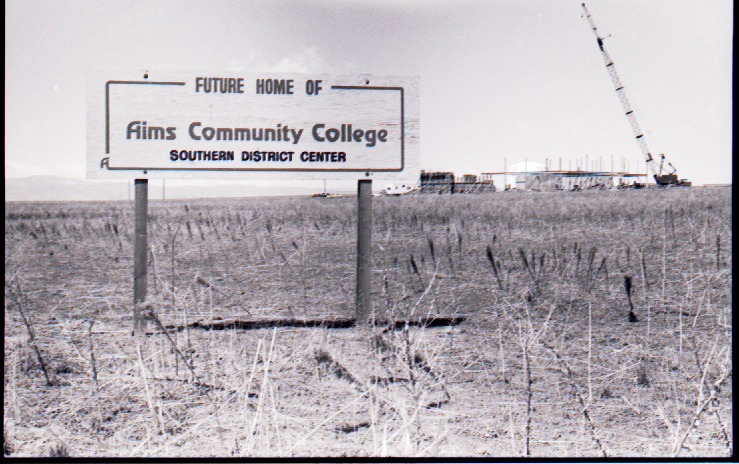 A sign in front of an open field announcing the expansion of Aims in Fort Lupton