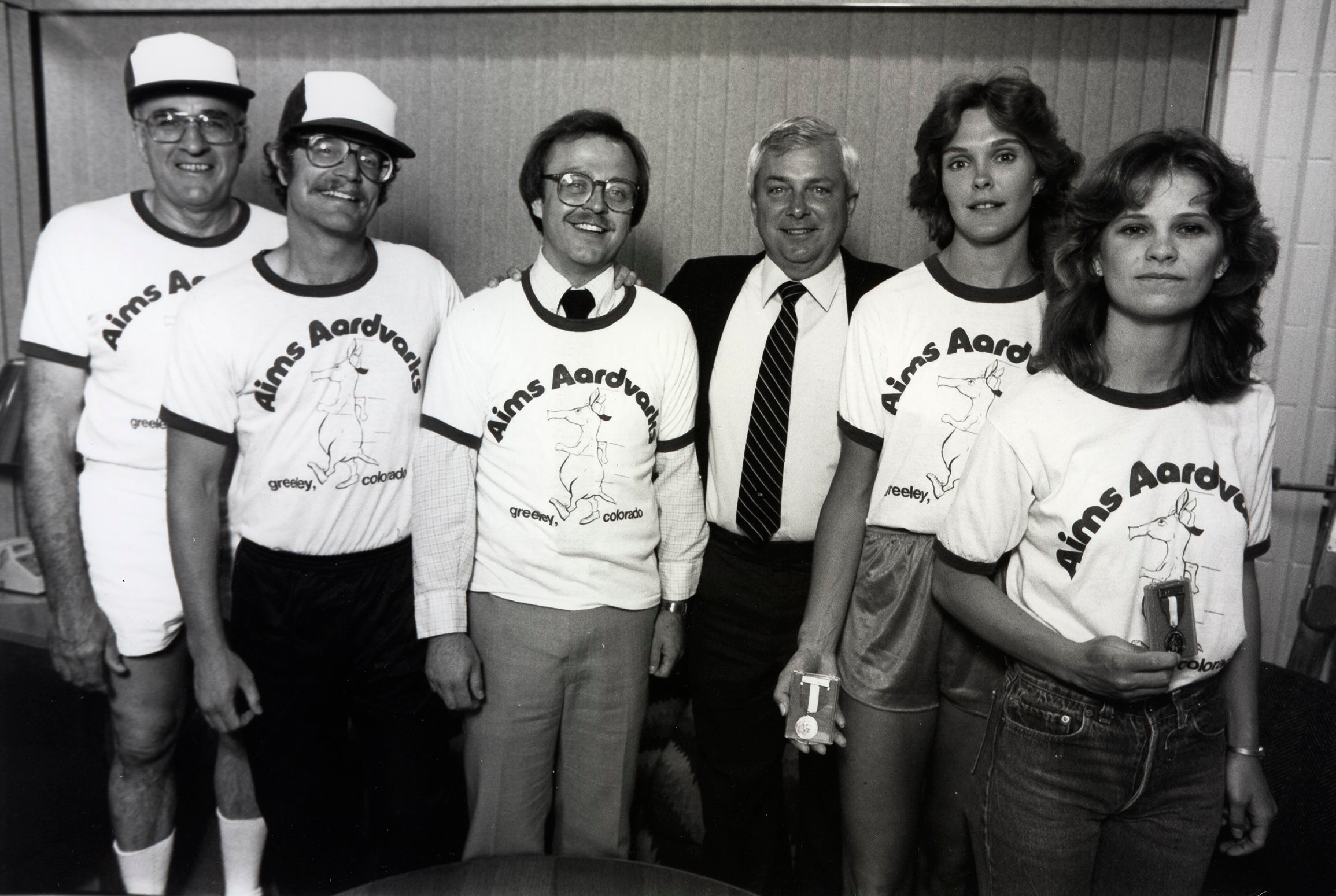 Former Aims President Dr. Conger posing with instructors who are wearing Aardvarks hats and tees in the 1990s