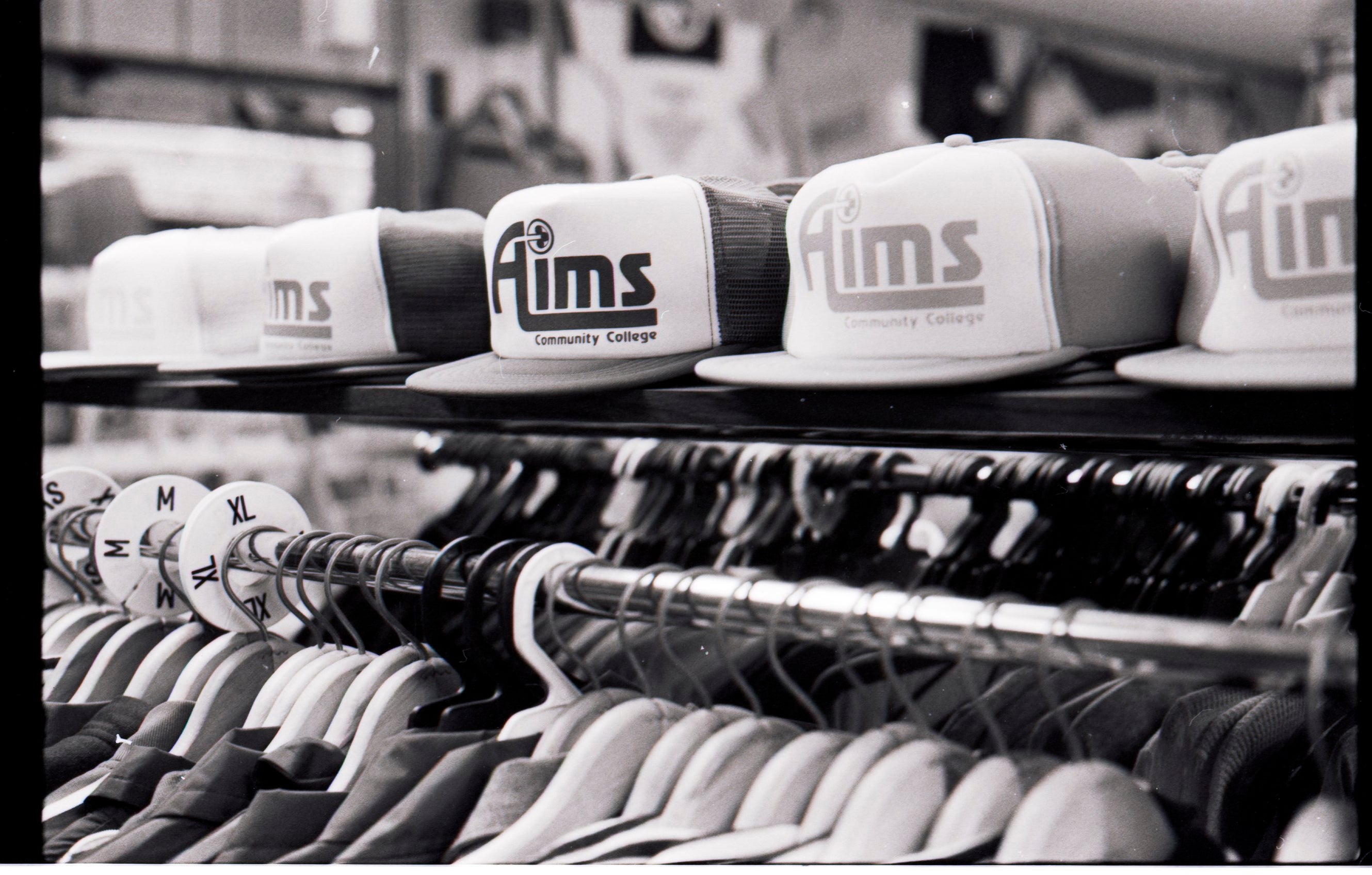 Hats and t-shirts displaying an old Aims logo in the Aims Bookstore in the 1990s.