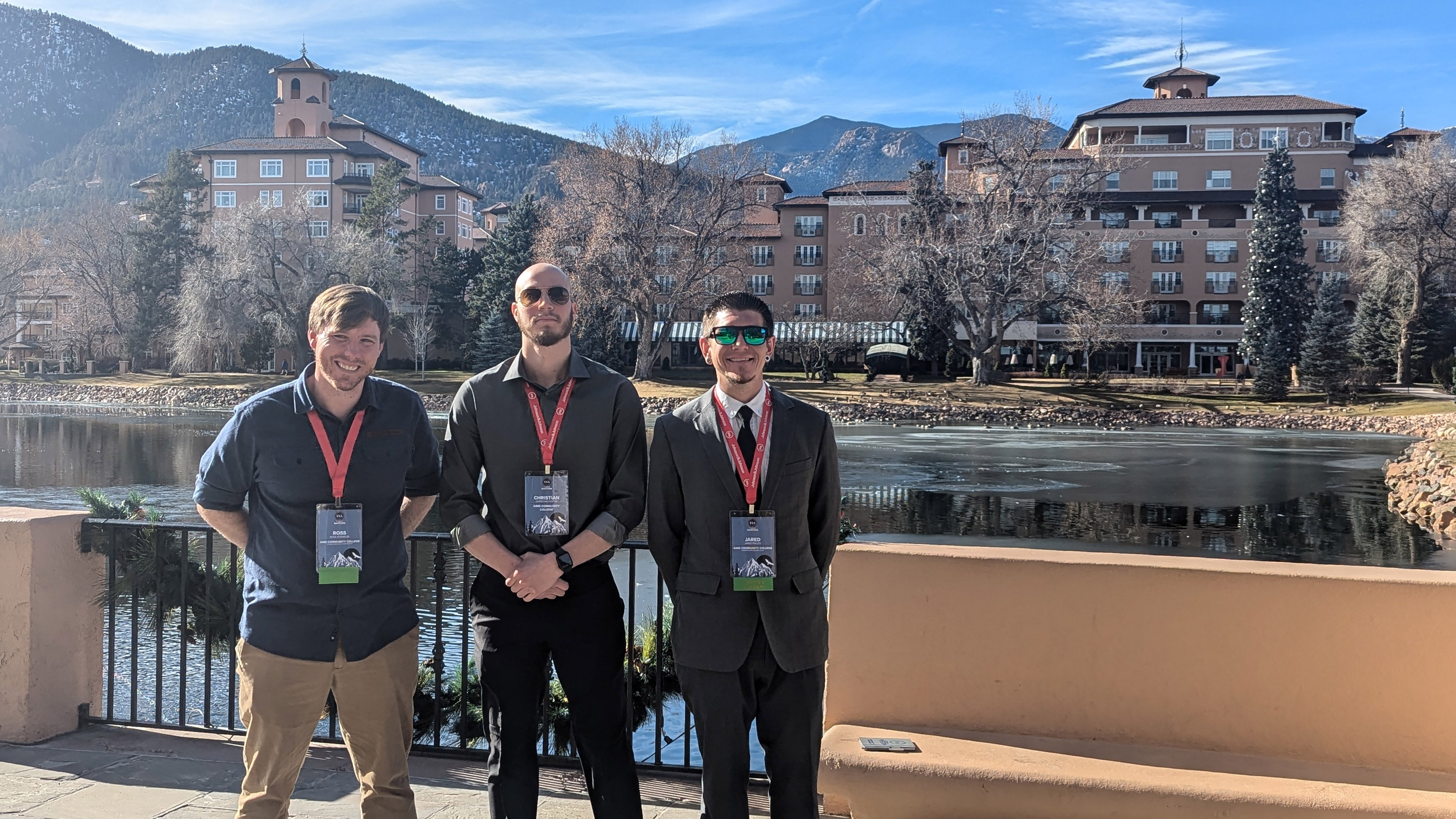 three men outdoors with mountains behind them