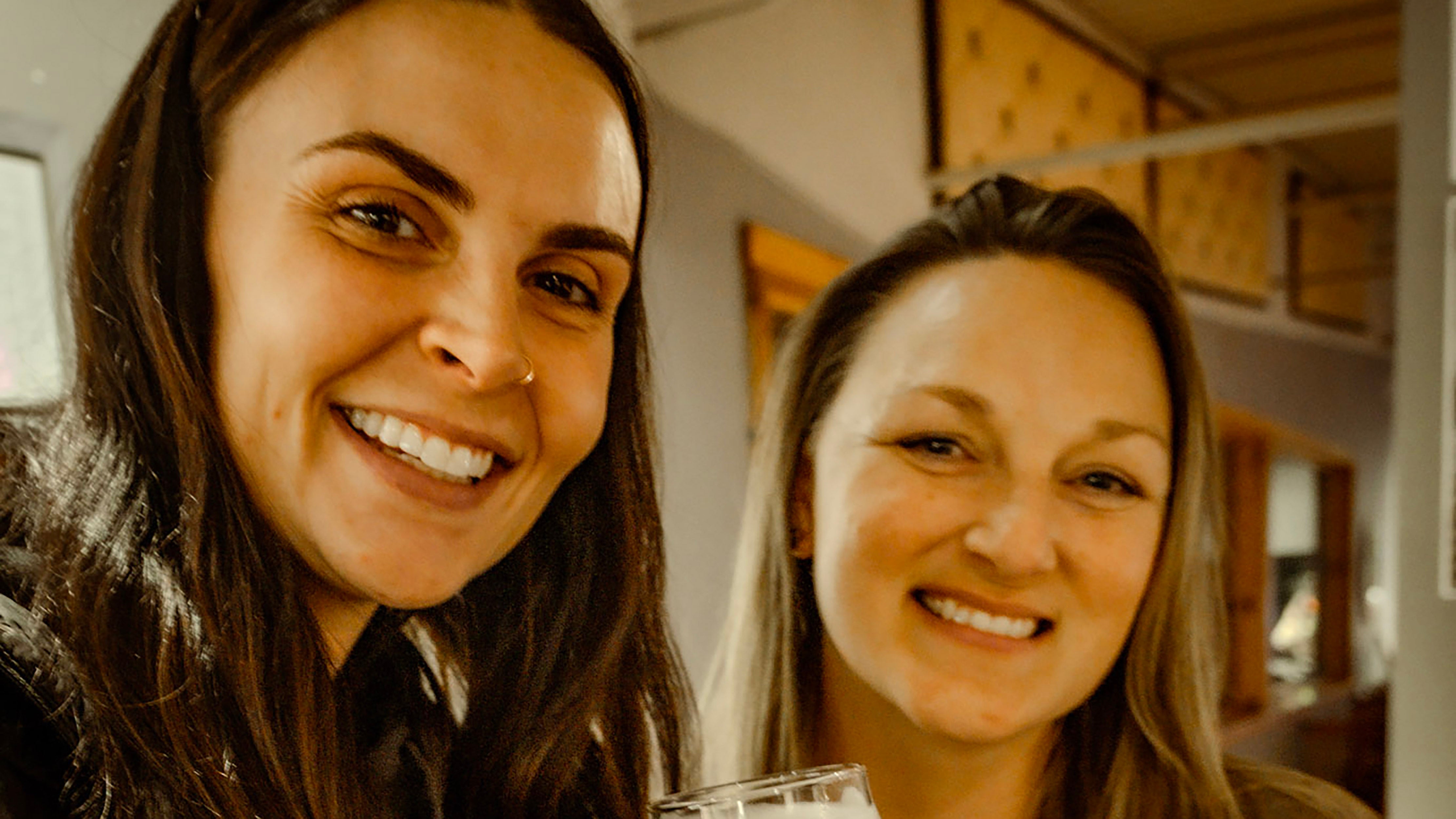 Close up of two women standing next to each other smiling at the camera