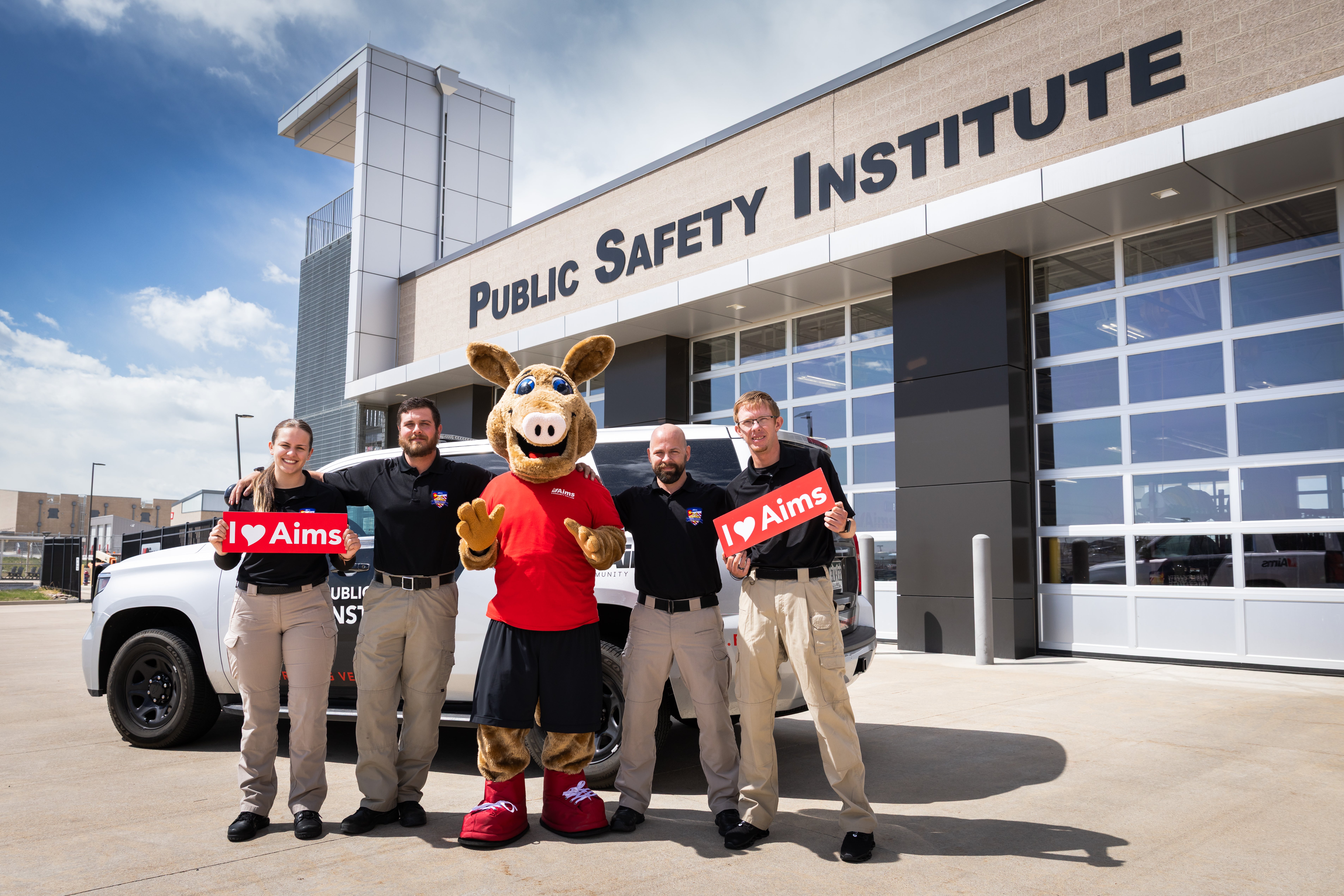 Aims faculty and students posing with Arty the Aardvark in front of the Public Safety Institute