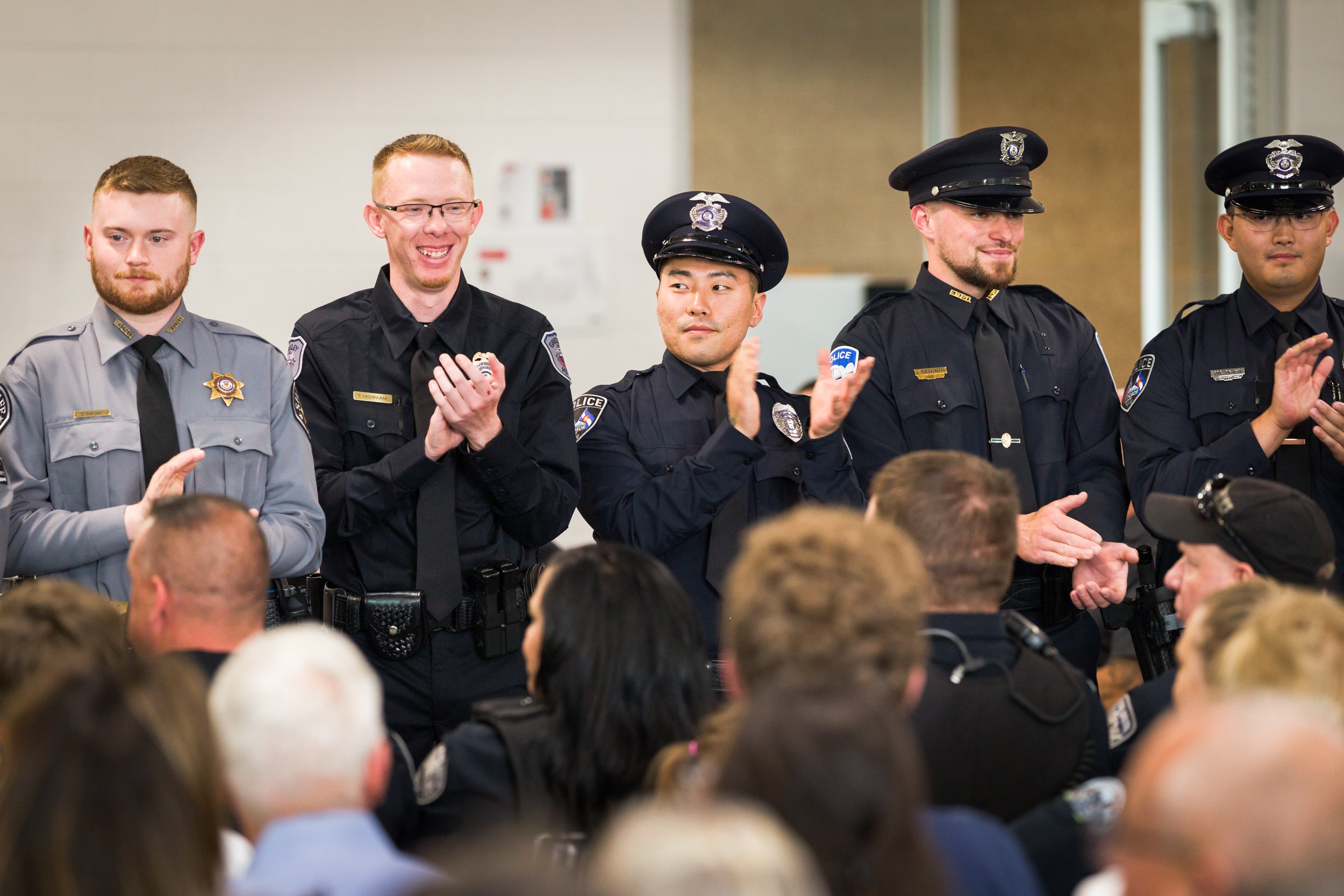 Aims Peace Officer Academy cadets in uniform applauding during a graduation ceremony