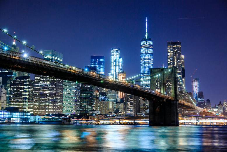 New York City Brooklyn Bridge skyline on the East River. One World Trade Center and other buildings in the background.
