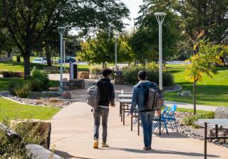 Two Aims students with backpacks using the walking path on the Greeley campus