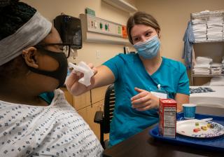Nurse aide student feeding a patient