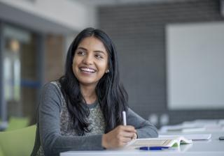 A smiling student smiles while doing coursework
