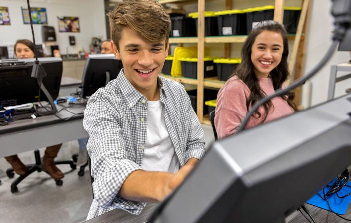 Cheerful student writing on computer monitor