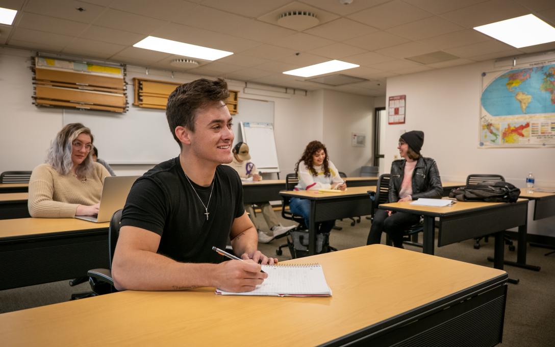 Aims students in a classroom smiling while engaging in a discussion