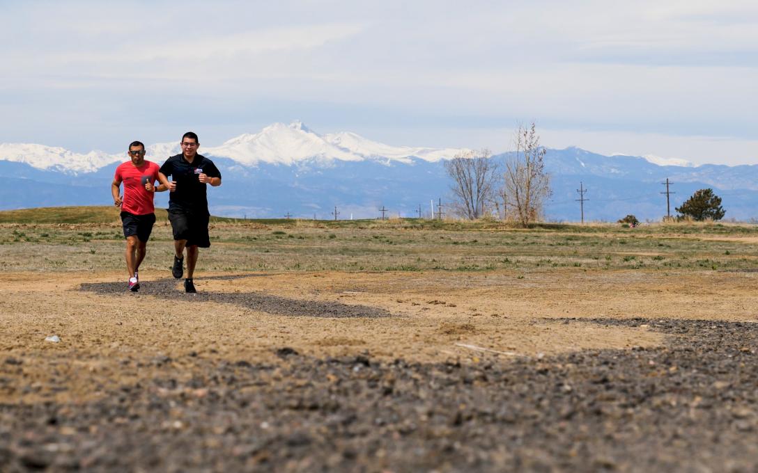 Two people jogging on a fitness trail on the Aims Fort Lupton Campus with the Rocky Mountains in the background