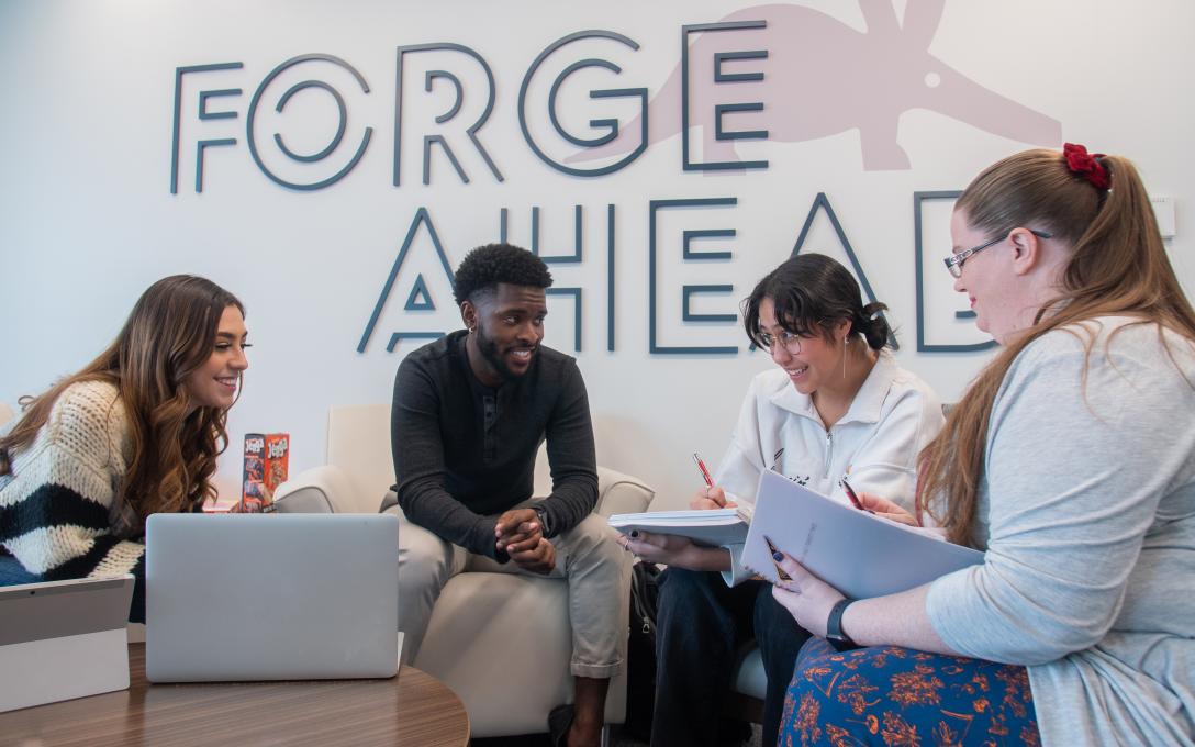 A group of students gathered for conversation in the Aims student lounge located in the Student Commons