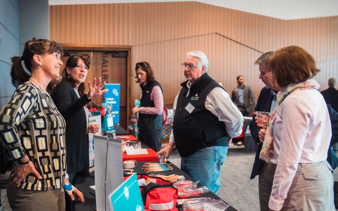 Donors talking to Aims employees about their departments at the Foundation's Arty's Spring Fling Donor Appreciation event.
