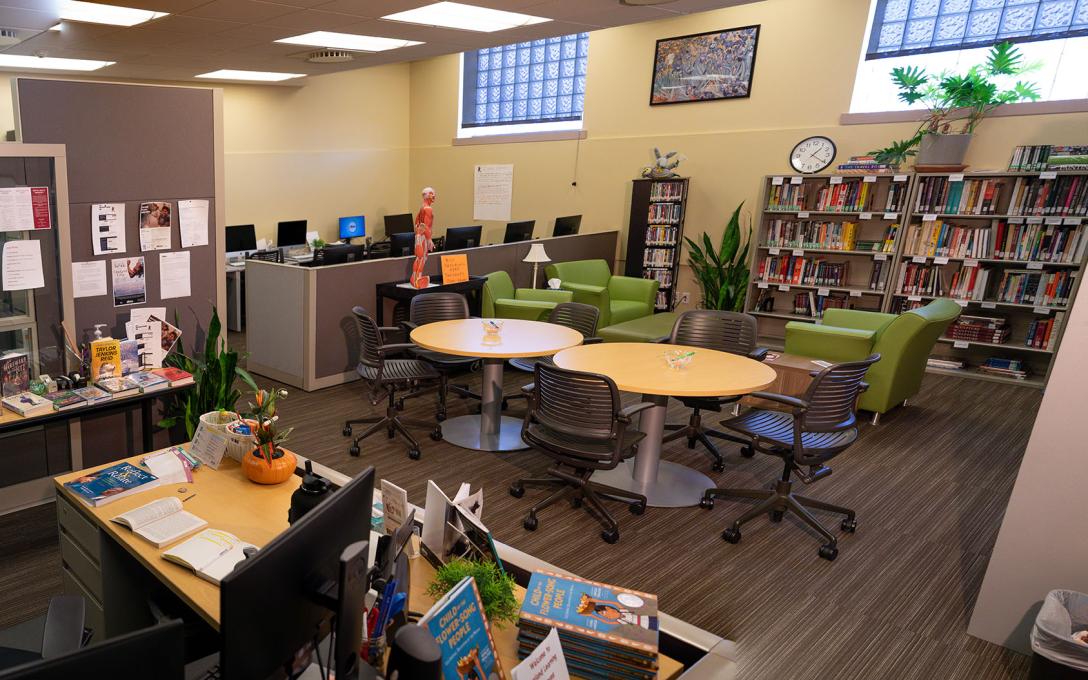 Wide view of the Learning Commons area including books, tables, chairs, and computers on the Aims Loveland campus.