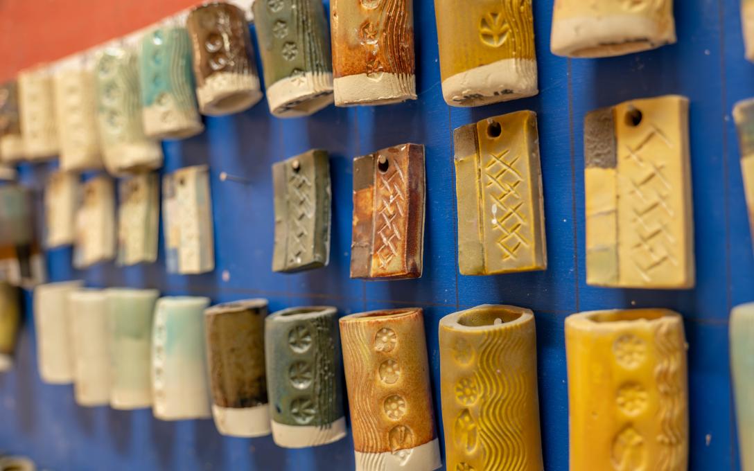 ceramic tiles with earth tone colored glazes hanging on blue wall