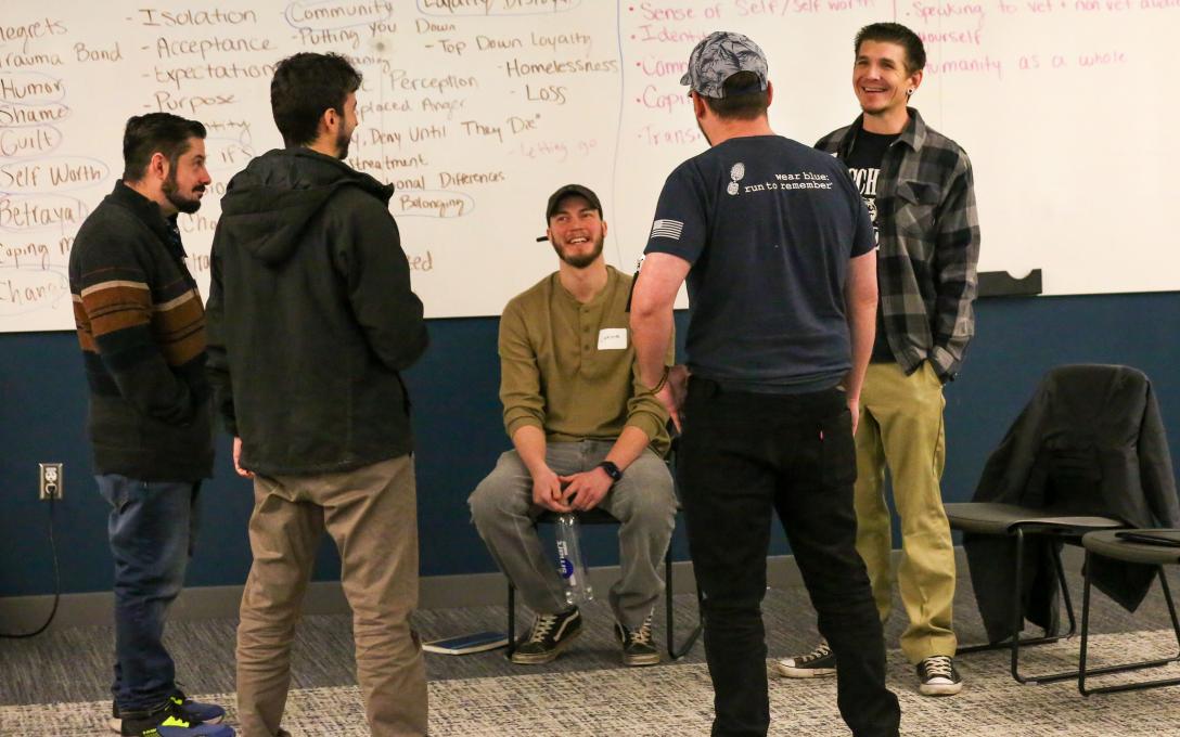 Veterans discuss a film project in a circle in front of a whiteboard