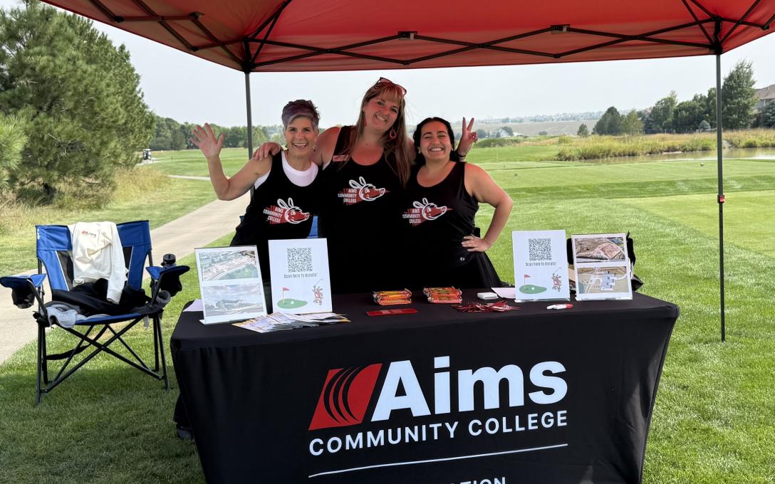 The Foundation staff members smiling and waving at a booth during the ECI Golf Tournament