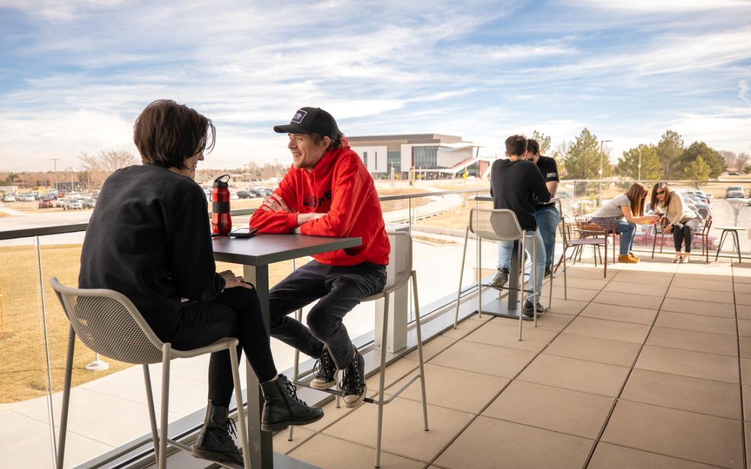 Students talking on the outside balcony of the Student Center at Aims Community College Greeley Campus