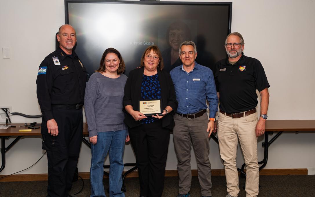 five people standing with award