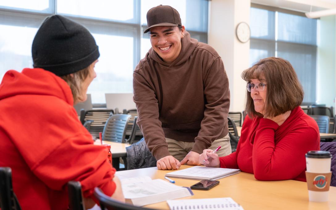 Students and teacher talk and smile at a table