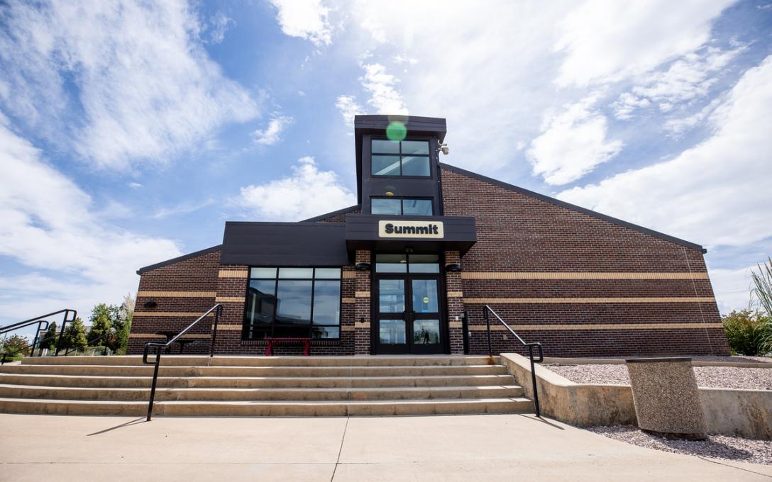 Exterior of the Summit Building with red brick, windows and black doors. Steps lead up to the doorway.