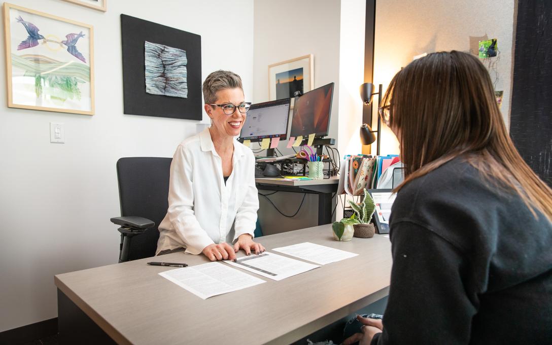 A Career Services staff assists a student with their resume in an office.