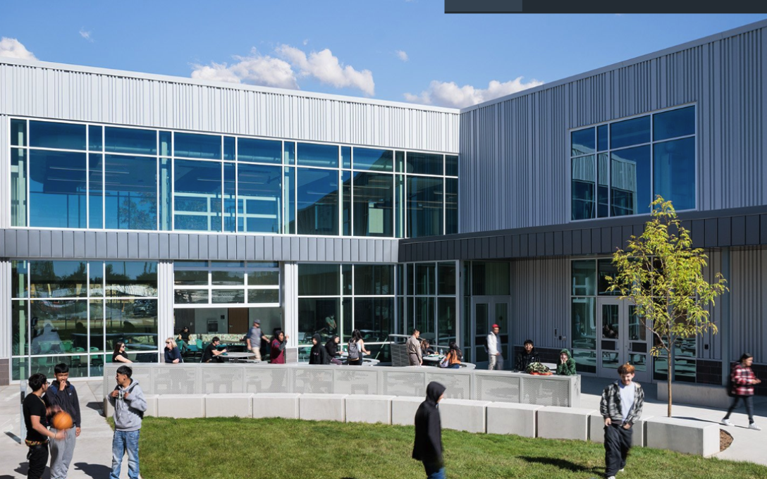 Career and Technical Education Center Greeley District 6 building with brick wall and glass wall with students standing on grassy common area