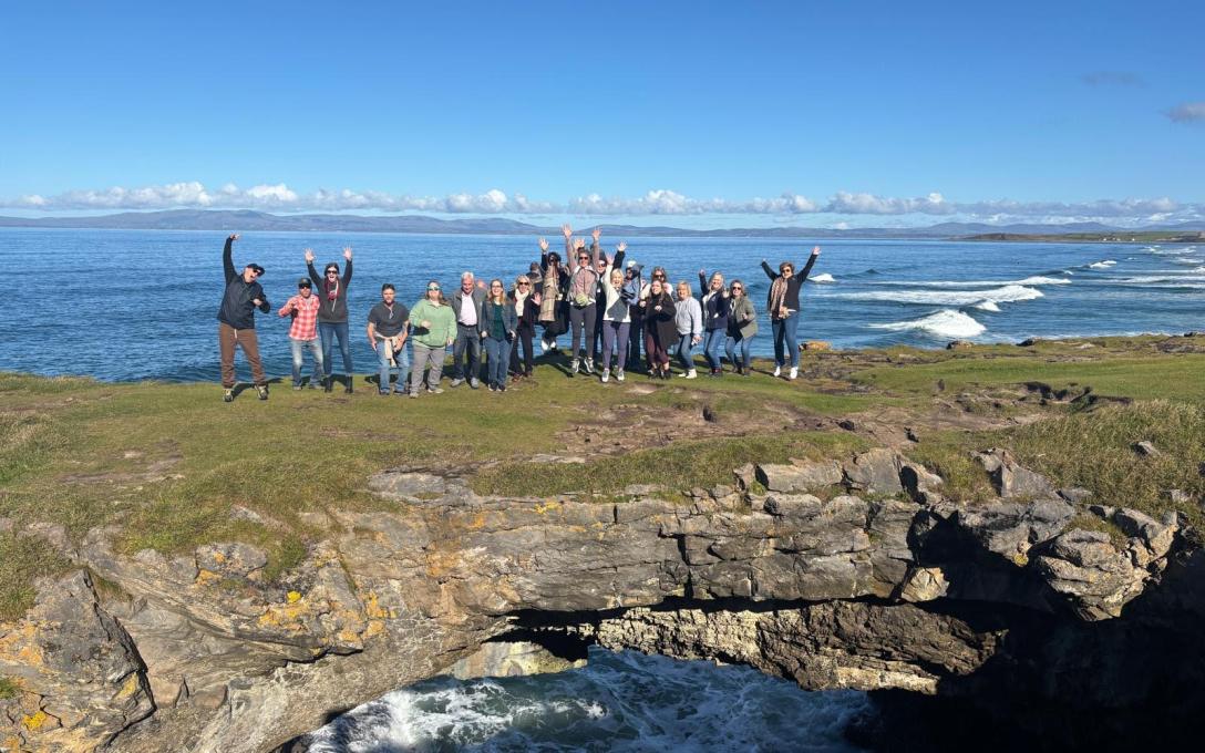 Group of students standing on grassy natural bridge over an ocean inlet called fairy bridge