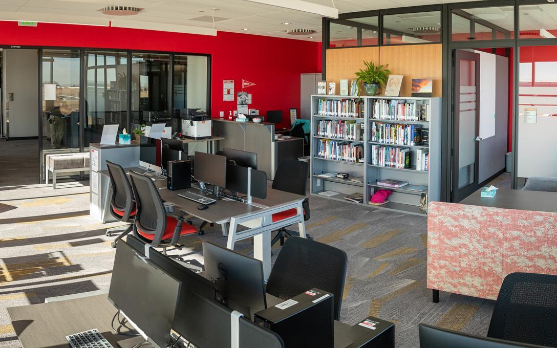 Aims Windsor Campus Learning Commons space with tables and chairs, bookcases, and computer stations