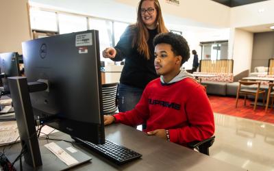 An Aims Financial Aid team member helping a student at a computer
