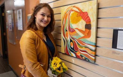 Hannah Woolf Best in Show Winner standing in gallery in front of art hanging on wall