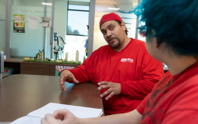 A man sits at a table talking with a student