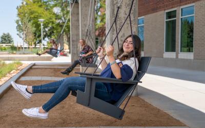 Students on swings outside the Student Commons building