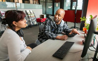 Advisor meeting with student poining to a computer screen