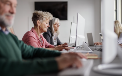 a row of senior citizen students sitting at table working on computers