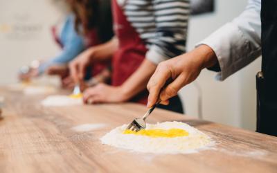 Closeup of hands mixing egg into flour with fork on wood counter