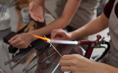 closeup of hands holding lit torch fusing glass