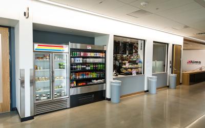 The storefront of Arty's Eatery, with a cooler for food and drinks, and a register to order fresh food.