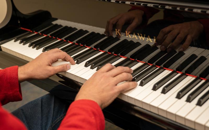 closeup of hands with red sleeves playing piano