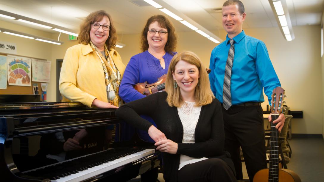 Aims Community College music faculty smiling while standing near a piano