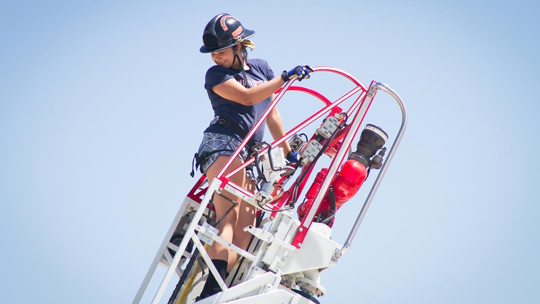 Aims fire science Xplore Academy student on an extension ladder