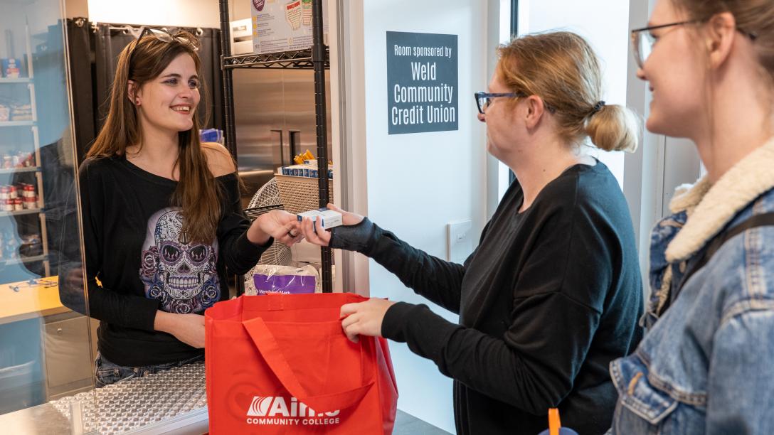 Two Students receiving items from Arty's Pantry staff