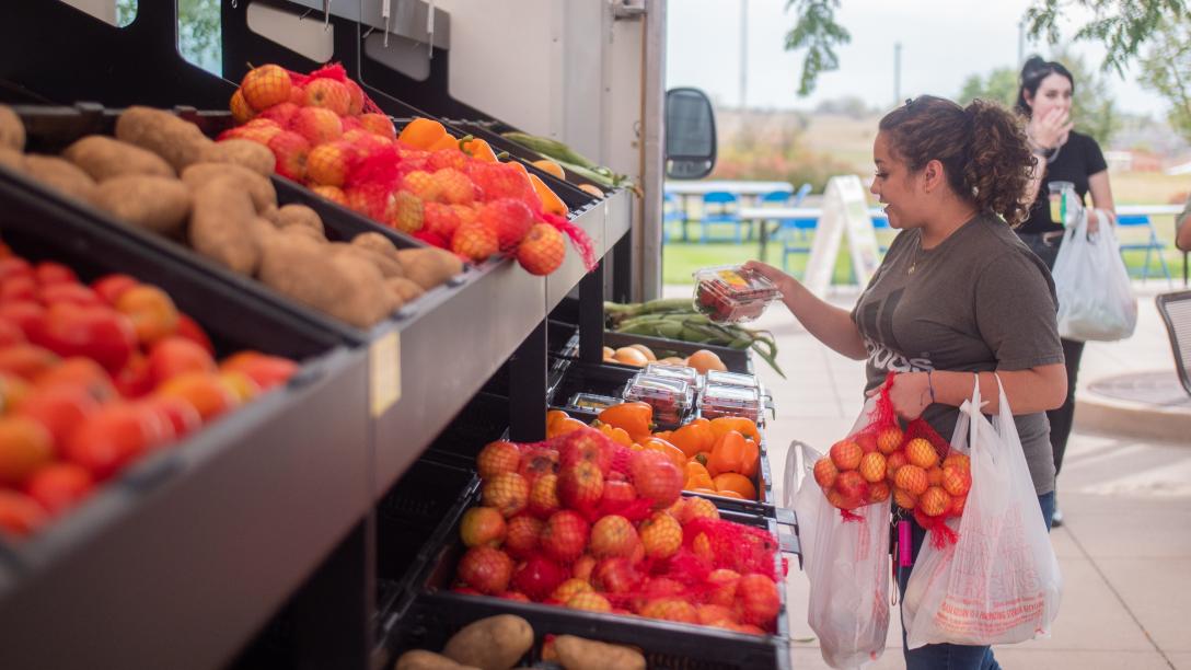 Farms to Families Food Truck with student choosing veggies