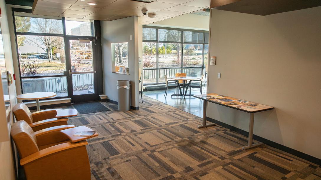 Exterior of the Student Lounge in Horizon Hall. There are chairs, tables, and vending machines.