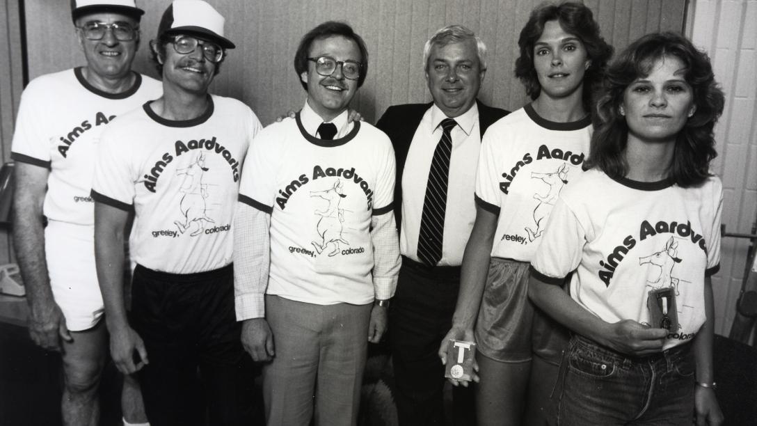 Former Aims President Dr. Conger posing with instructors who are wearing Aardvarks hats and tees in the 1990s