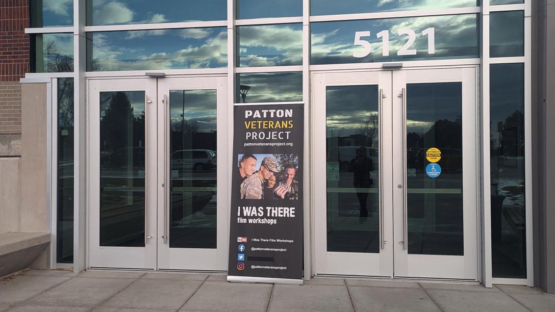 2 sets of double doors on either side of a tall banner that reads "Patton Veterans Project - I was there film workshops"